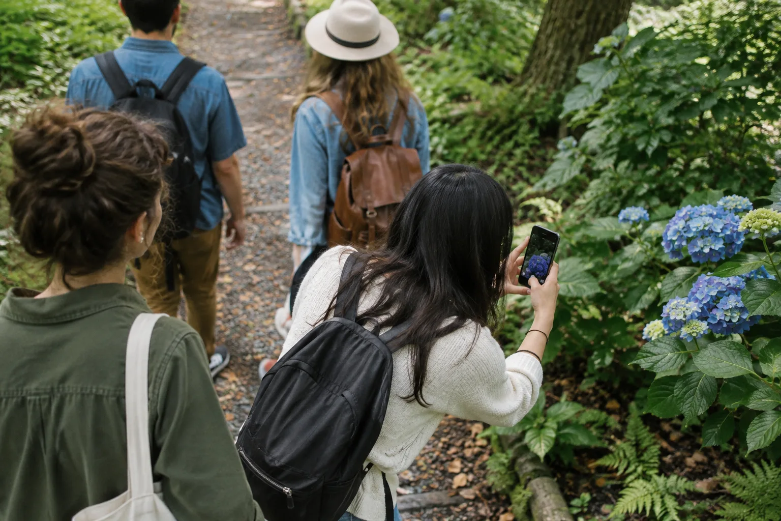 Des promeneurs photographient un détail coloré au bord d’un chemin dans un parc.